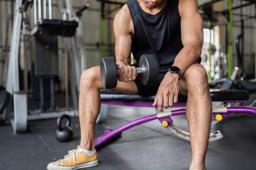 A young man focuses on his form while performing a dumbbell curl, emphasizing strength training and fitness dedication.