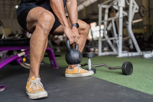 A young man demonstrates strength and focus while lifting a kettlebell in a gym, emphasizing his commitment to fitness.