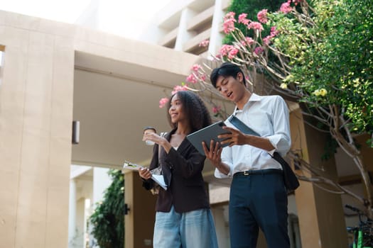 A woman and a man review their tablet while discussing sustainable practices, highlighting the integration of technology in modern workplaces.