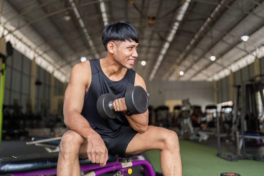 A young man smiles while lifting a dumbbell, showcasing a positive attitude towards fitness and strength training.