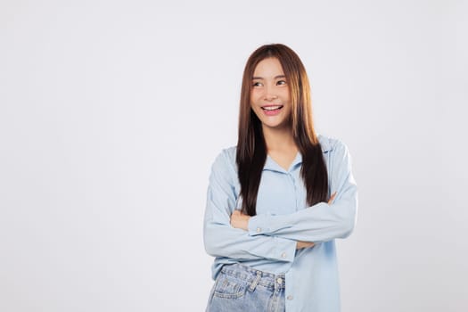 Asian woman posing confidently with crossed arms, expressing positivity and power with crossed arms and warm smile against isolated white backdrop.