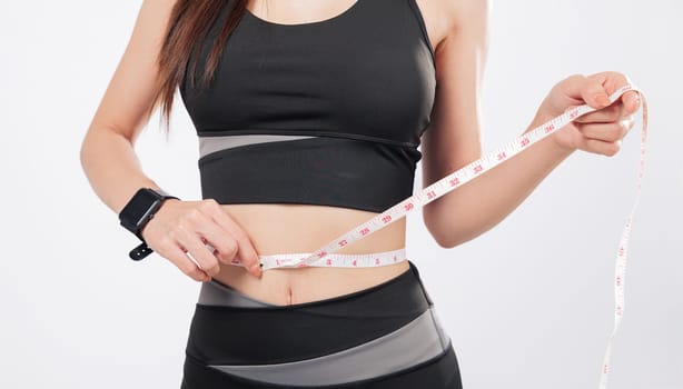 Tape for tracking and tape for success, this smiling woman in sport attire proudly measures her slim waist, celebrating weight loss and healthy living. isolated studio white background