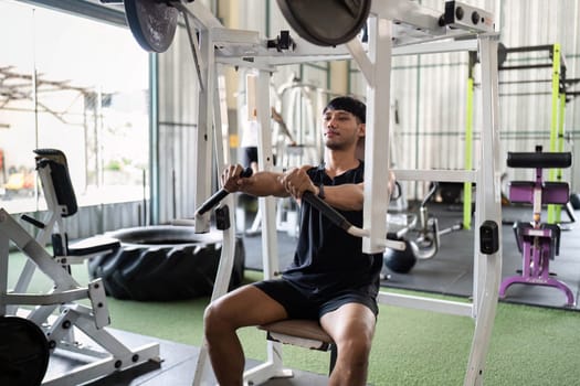 A focused young man performs seated rows at a gym, showcasing dedication to fitness and strength training.