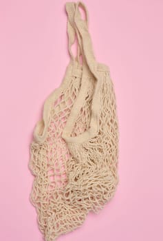 Empty reusable cotton mesh bag on pink background, top view