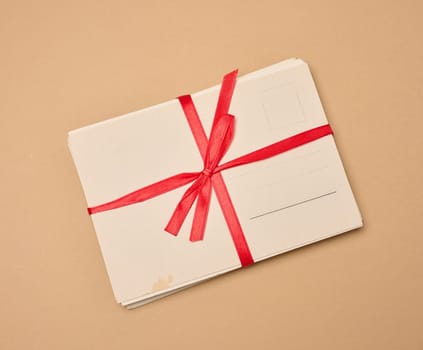A stack of blank postcards tied with a red ribbon and bow lies on a neutral background.