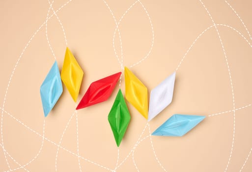 Multicolored origami paper boats with dotted lines symbolizing routes on a neutral background.