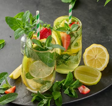A refreshing drink in a glass with lemon slices, strawberries, fresh mint leaves, and sparkling water, top view