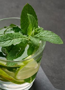Refreshing mojito cocktail with lime, mint, strawberry, and ice on dark background, top view