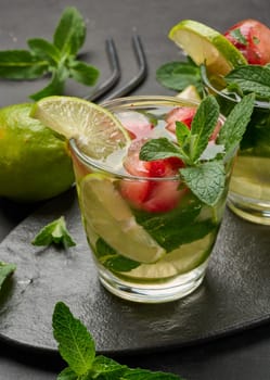Refreshing mojito cocktail with lime, mint, strawberry, and ice on dark background