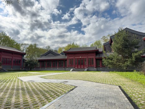 Spacious courtyard with traditional Chinese style buildings featuring red columns and tiled roofs. The open area is paved with geometric patterns, enhancing the architectural elegance