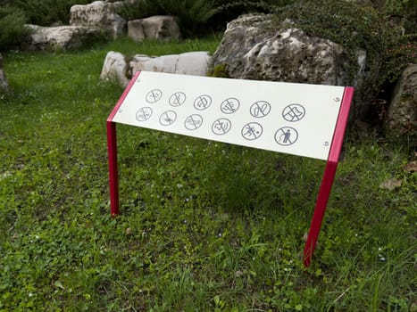Prohibition sign in a public park with visual icons indicating restricted activities such as cycling, fishing, and littering. Clear visual design promotes safety and respectful park use