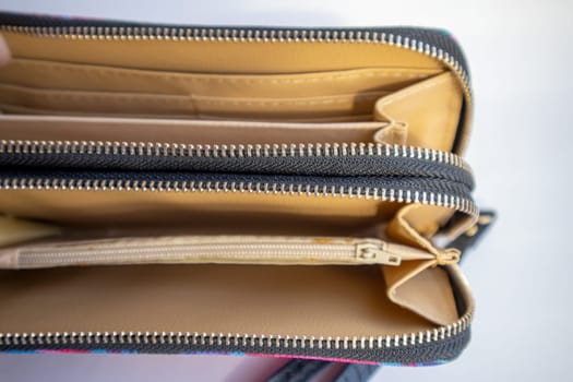 Fashionable outdoor women's empty wallet with gold zippers, top view, on white background.