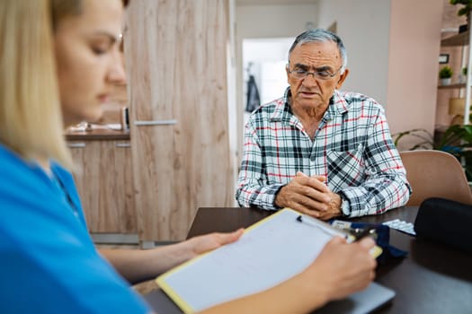 Senior gentleman discusses his health with a caregiver.