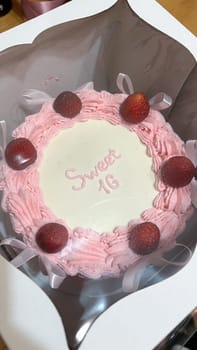 A stunning Sweet Sixteen cake, adorned with fresh strawberries and pink frosting. This elegant cake with ribbon accents is perfect for making any birthday celebration truly special.
