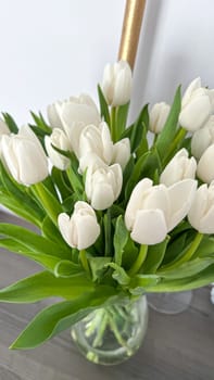 Brighten your space with a beautiful bouquet of fresh white tulips in a clear glass vase. Ideal for home or office decor, this floral arrangement brings elegance and freshness.