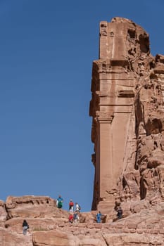 Petra, Jordan - 10 November 2024: Tomb opposite the Theater Necropolis in the Street of Facades in Petra with tourists climbing to view