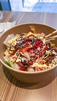 A fresh poke bowl filled with seafood, crunchy vegetables, and topped with black and red sesame seeds. This colorful dish is perfect for a healthy meal, offering a blend of flavors and textures.