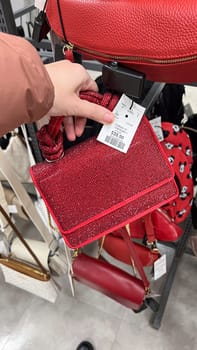 Ottawa, ON Canada - May 01, 2025: Stylish red handbag rhinestones with handles displayed in a retail store, showcasing modern design and luxury accessories for fashion enthusiasts and shoppers.