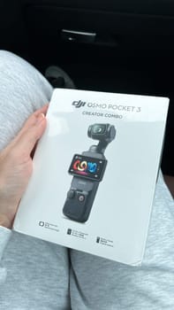Ottawa, Canada - April 05, 2025: A hand grips a DJI Osmo Pocket 3 camera, resting on a lap with a sleek black carrying case, highlighting innovative design for capturing steady videos