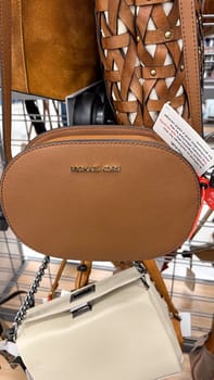 Ottawa, ON Canada - May 01, 2025: Stylish brown handbag with Michael Kors logo displayed on a rack in a retail store, showcasing modern design and luxury accessories for fashion enthusiasts and shoppers.