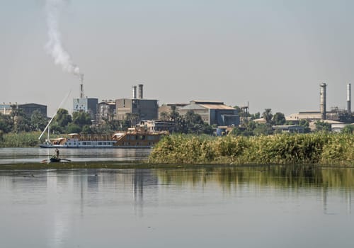 Edfu,. Egypt - 6 November 2024: Edfu steel factory, including industrial buildings, smokestacks, seen from the Nile River
