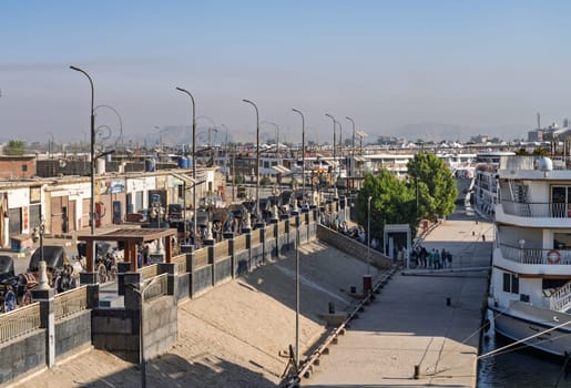 Edfu, Egypt - 6 November 2024: Cruise ships docked side by side with horses and carriages waiting in congested harbor
