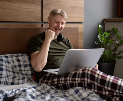 Happy Man Using A Laptop In Bed At Home