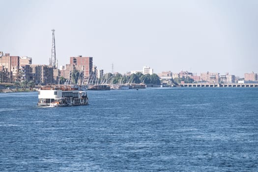 Modern waterfront buildings and dock in Esna as a Dahabiha approaches the old dam across Nile