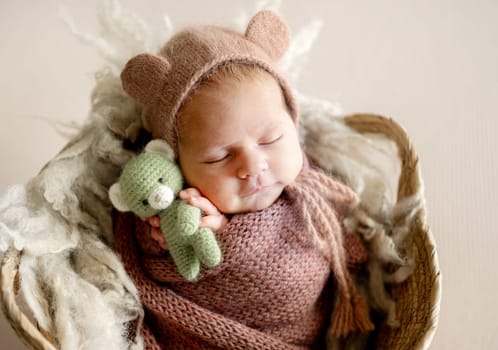 Newborn Baby Sleeping In Fawn's Basket In A Studio Photo