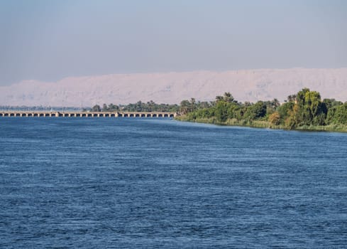 Old Esna dam and lock across the Nile River with sandy hills of Sahara desert behind