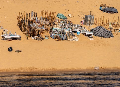 Collection of Egyptian gifts and trinkets on the sandy beach by Nile River in the Nubian village near Aswan