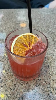 Indulge in a vibrant cocktail drink featuring crushed ice, a straw, and a decorative orange slice. A thirst-quenching beverage to savor during sunny getaways or moments of pure relaxation. Enjoy