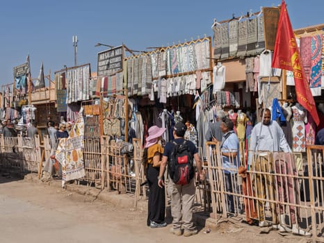 Edfu, Egypt - 6 November 2024: Tourists walking past shops outside the entrance to the temple in Edfu