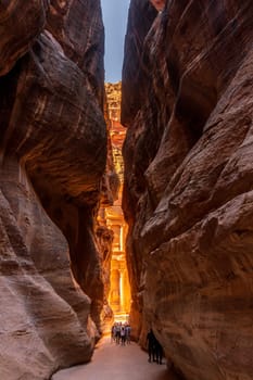The carved facade of the Treasury building or Al-Khazneh in the ancient city of Petra in Jordan seen through narrow Siq gorge