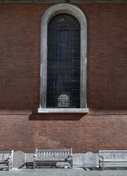 London, UK - May 13, 2025 - a view from the side of St Paul's Church is England parish church with tall glass window on red brick wall and wooden benches in Bedford Street. use it as your Wallpaper, Poster and Space for text, Selective focus.