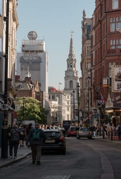 London, UK - May 13, 2025 - A crowd of people and tourists are walking on St Martin's Lane with Scenery view of St Martin-in-the-Fields and Ancient buildings. use it as your Wallpaper, Poster and Space for text, Selective focus.