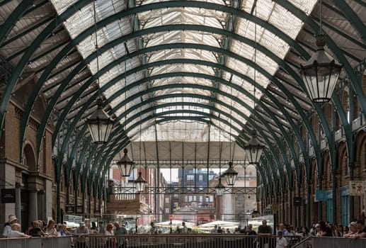London, UK - May 13, 2025 - The vintage iron glass roof with Lamps on the ceiling of Apple market in Covent Garden Market Hall. View of Metallic framework arch roof with ceiling hanging lamp, use it as your Wallpaper, Poster and Copy space, Selective focus.