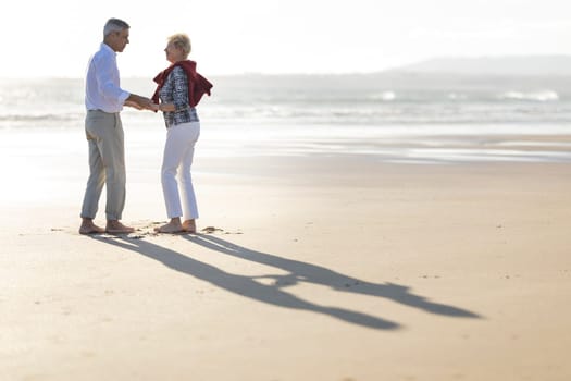 Happy retired couple enjoying a romantic moment on a beautiful beach at sunset
