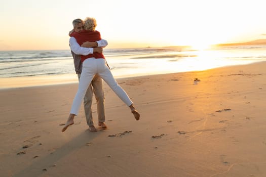 Elderly couple enjoying a romantic moment, embracing on the beach at sunset