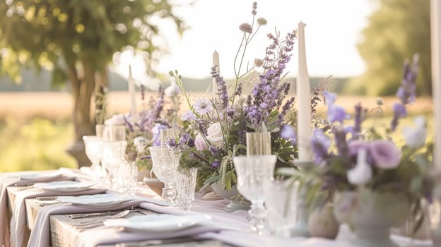 Elegant wedding dining table with candles floral arrangements in shades of purple, lavender and pink in a garden