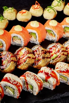 Delicious assortment of sushi rolls presented on a black stone surface, showcasing diverse ingredients and culinary techniques