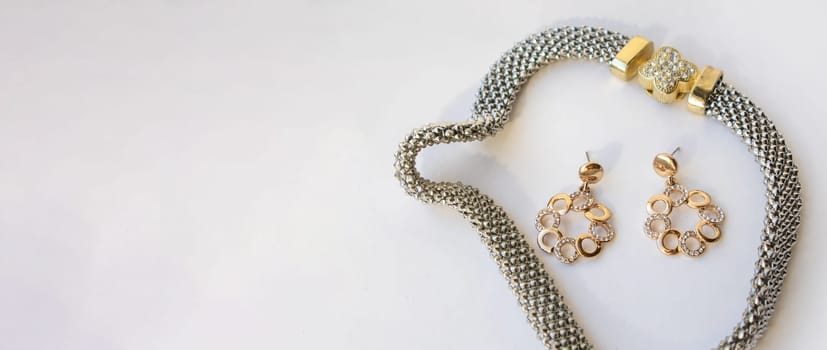Banner with romantic jewelry set of sterling silver choker necklace and round chain earrings on white background, copy space.