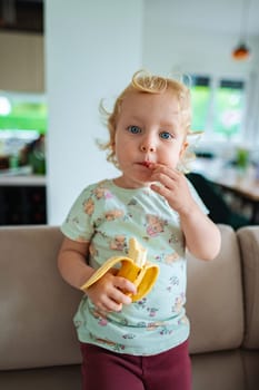 Little one savors tasty banana while exploring indoors.