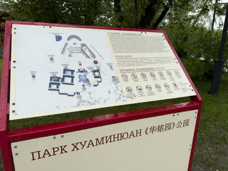 Moscow, Russia, April 25, 2025: Closeup of bilingual information stand at Huamin Park in Moscow shows detailed layout map and list of rules in Russian and Chinese with symbolic icons