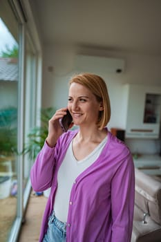 Woman in a bright room enjoys a phone conversation.
