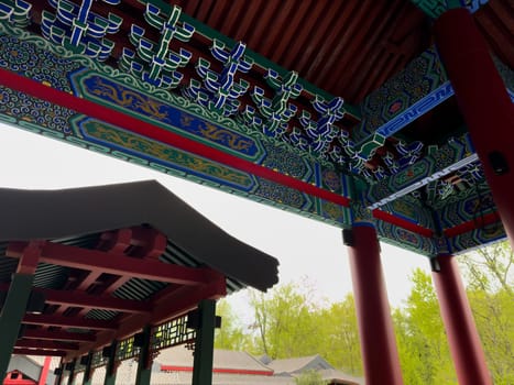 Moscow, Russia, April 25, 2025: Ornamental ceiling details with traditional Chinese motifs and dragons captured under covered walkway in Huamin Park, architectural richness and cultural aesthetics