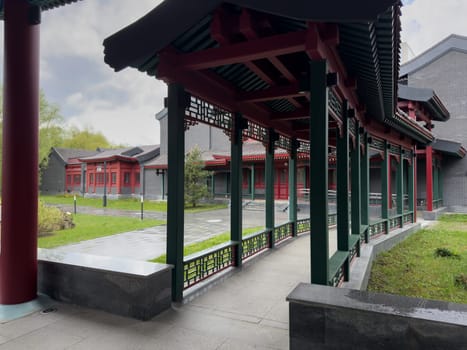 Moscow, Russia, April 25, 2025: Covered gallery in Chinese architectural style with red and green columns, decorative lattice panels and tiled roof, located in public cultural park in Moscow