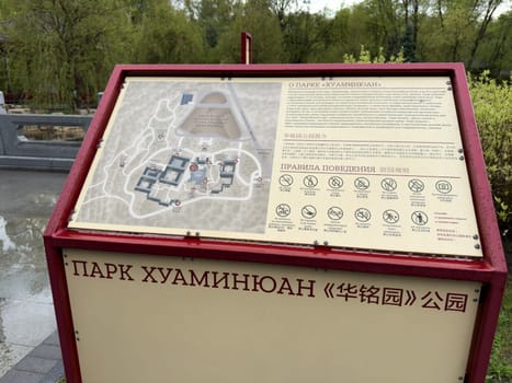 Moscow, Russia, April 25, 2025: Informational board with map and visitor rules at Huamin park in Moscow, designed in Chinese style and placed near scenic landscape and traditional architecture