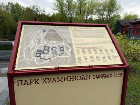 Moscow, Russia, April 25, 2025: Close up of bilingual information stand with map and park rules at entrance to Huamin park in Moscow, featuring Chinese cultural motifs and graphic symbols