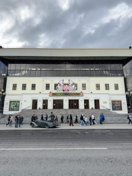 Moscow, Russia, April 25, 2025: Facade of the Nikulin Moscow Circus with visitors walking by and the monument to Yuri Nikulin in front of the historic entrance on Tsvetnoy Boulevard